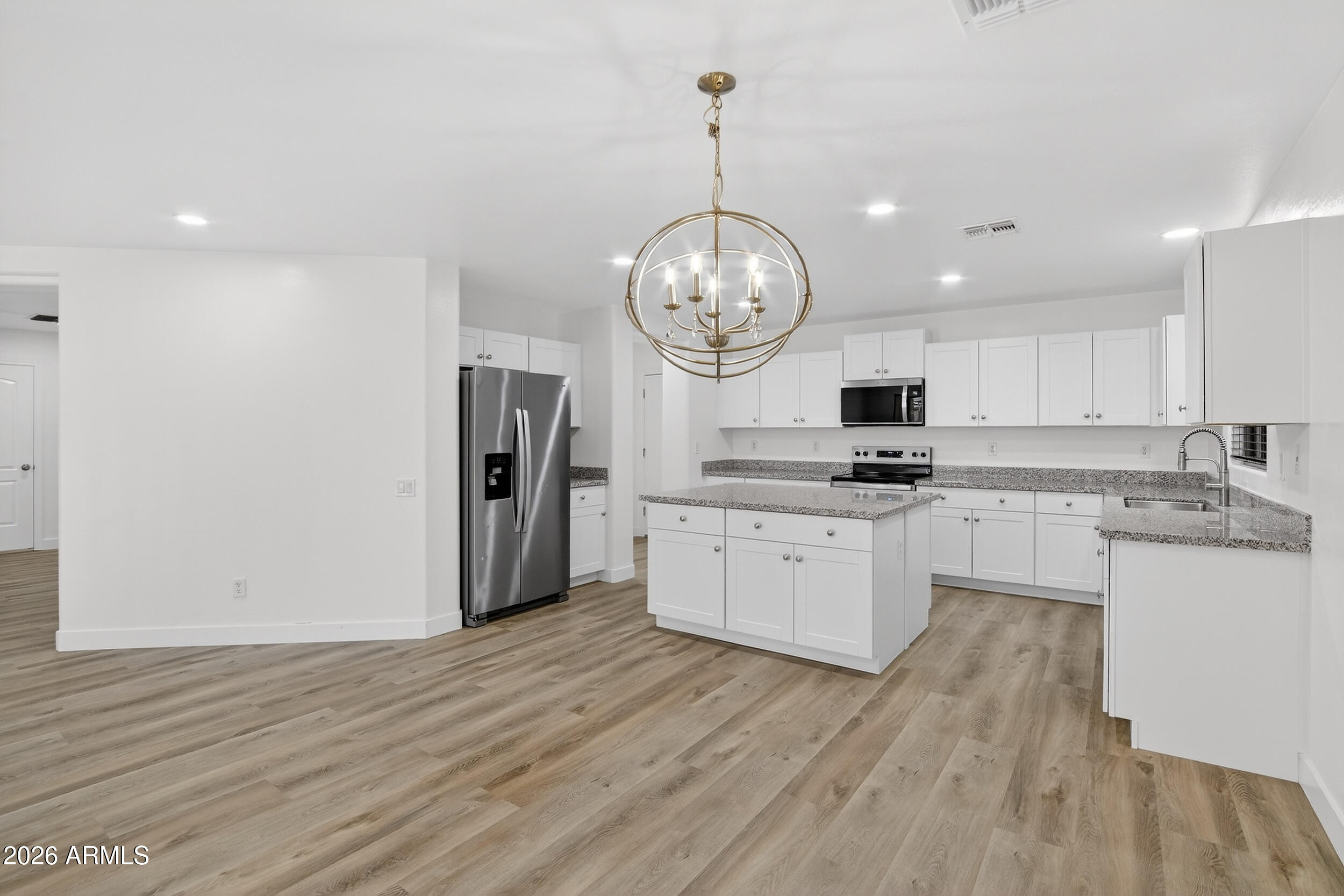 43620 West Cowpath Road Maricopa, AZ 85138 - Photo 15 of 60 a kitchen with stainless steel appliances granite countertop a refrigerator a stove and white cabinets with wooden floor