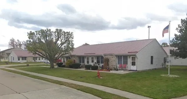 a front view of a house with a garden and trees