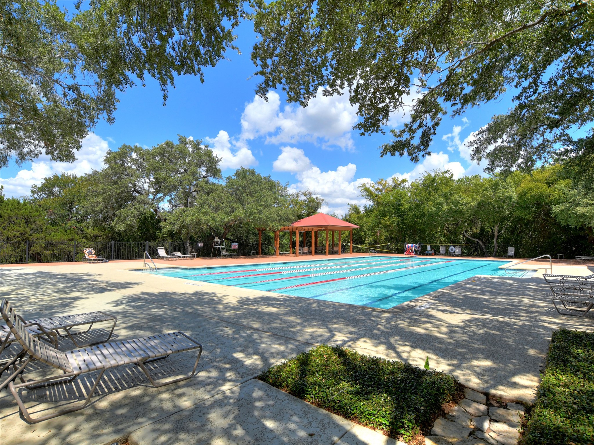 2849 Grimes Ranch Road Austin, TX 78732 - Photo 35 of 37 Swim laps under clear skies in the community pool, bordered by lush trees and a relaxing pergola.