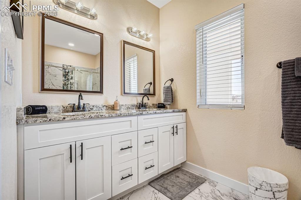 10108 Rolling Ridge Road Colorado Springs, CO 80925 - Photo 13 of 32 a bathroom with double sink and a mirror