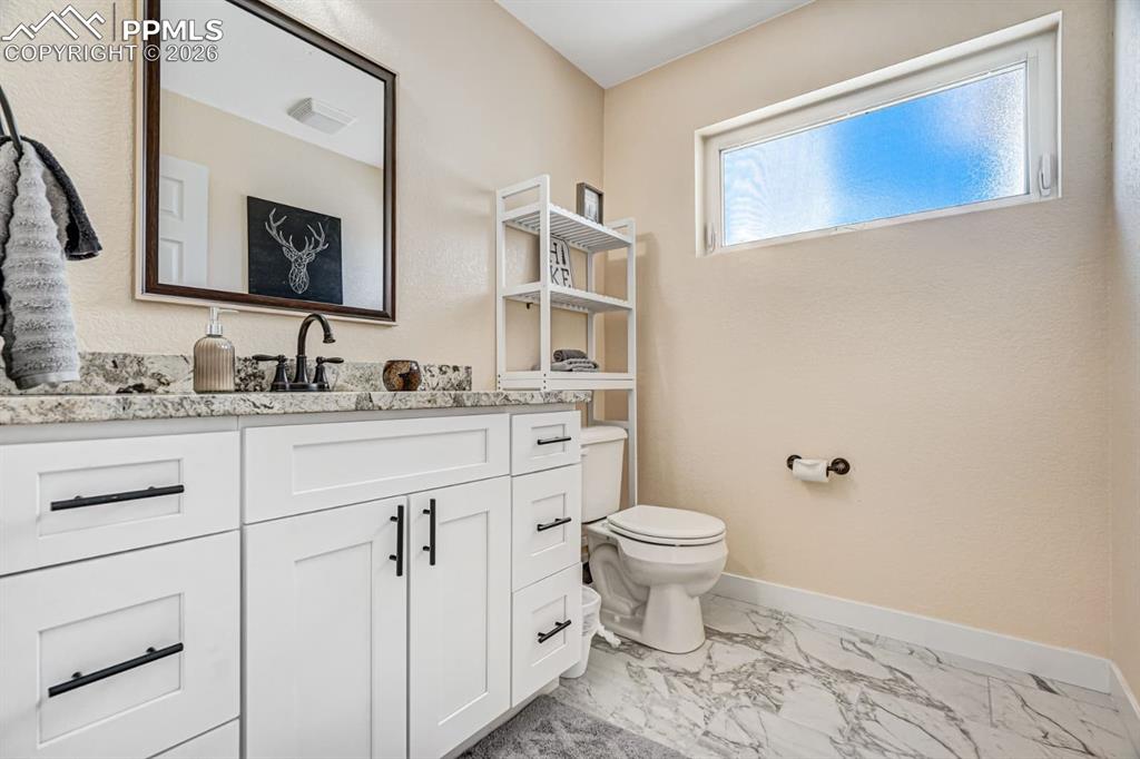10108 Rolling Ridge Road Colorado Springs, CO 80925 - Photo 14 of 32 a bathroom with a toilet sink double vanity and mirror