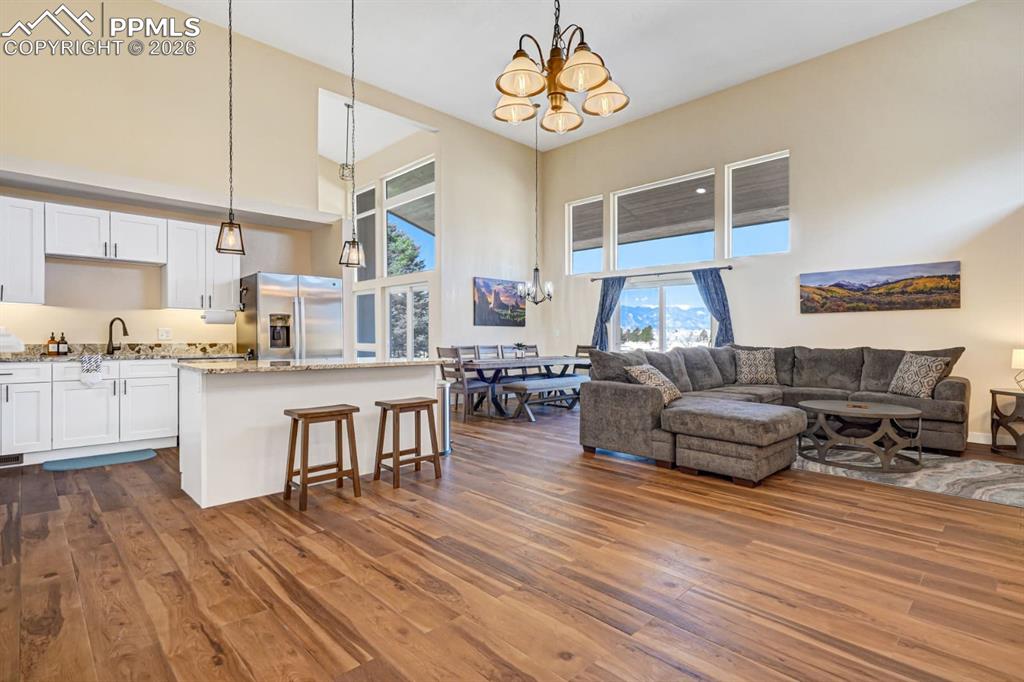 10108 Rolling Ridge Road Colorado Springs, CO 80925 - Photo 3 of 32 a living room with kitchen island furniture and a wooden floor