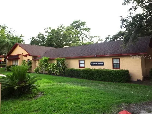 a view of a yard in front of a house with plants and large tree