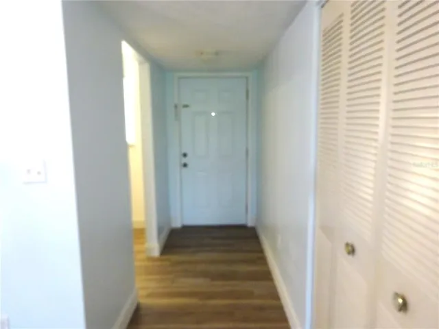 a view of a hallway with wooden floor and a bathroom