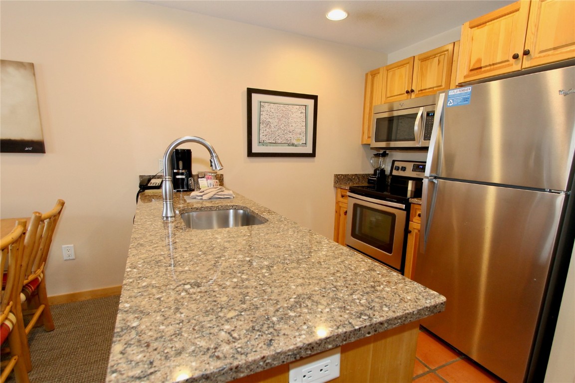 172 Copper Circle, Unit 301 Copper Mountain, CO 80443 - Photo 4 of 23 a kitchen with stainless steel appliances granite countertop a refrigerator a stove and a sink with wooden floor