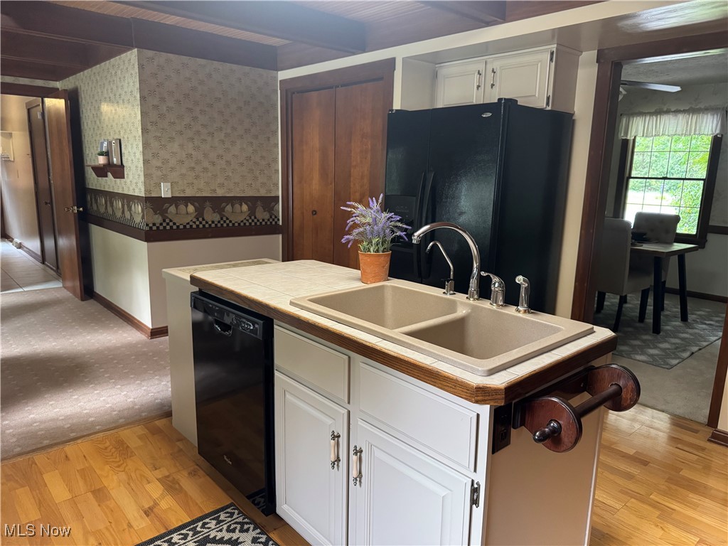 7345 Roller Road Salem, OH 44460 - Photo 13 of 50 Kitchen with black appliances, white cabinets, light wood-type flooring, wallpapered walls, and tile counters