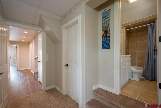 a view of a hallway with wooden floor and a bathroom