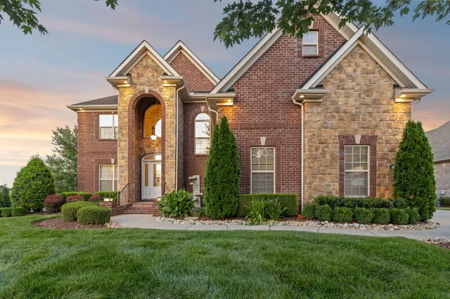 a view of a white house next to a yard with big trees