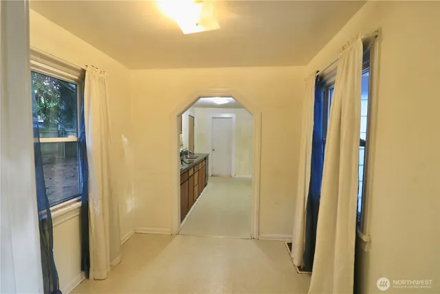 a view of a hallway to a livingroom with furniture and windows
