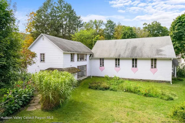 a backyard of a house with plants and large tree