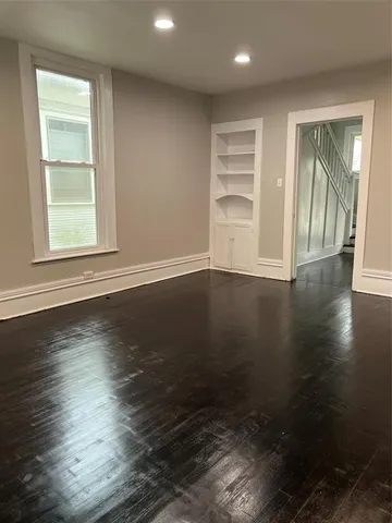an empty room with wooden floor closet and windows