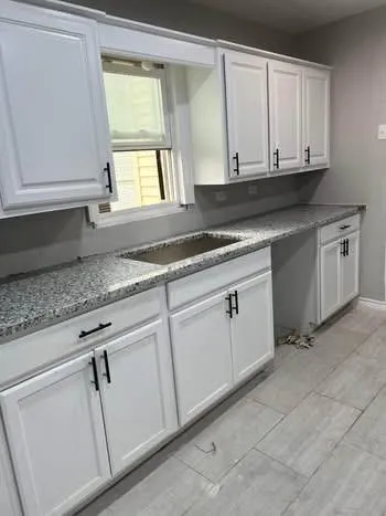 a kitchen with granite countertop white cabinets and white appliances