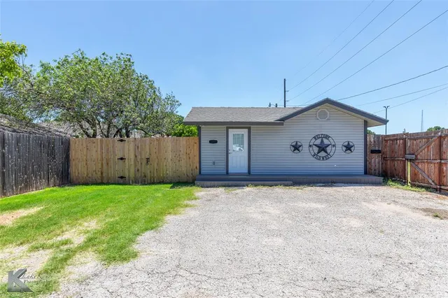 a view of a backyard with a fence and a large tree