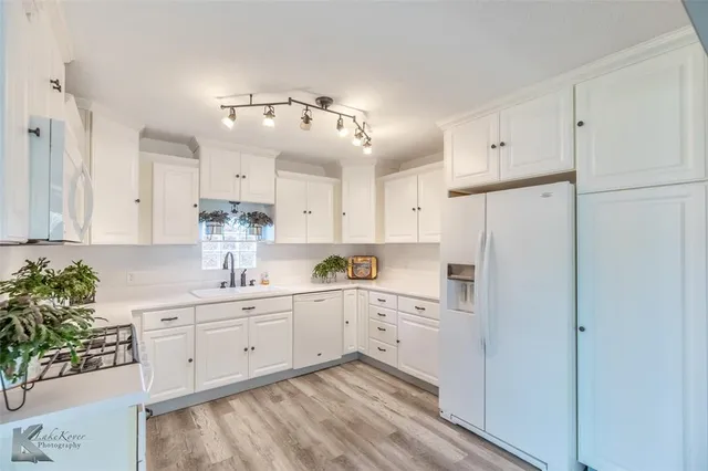a kitchen with white cabinets and chandelier