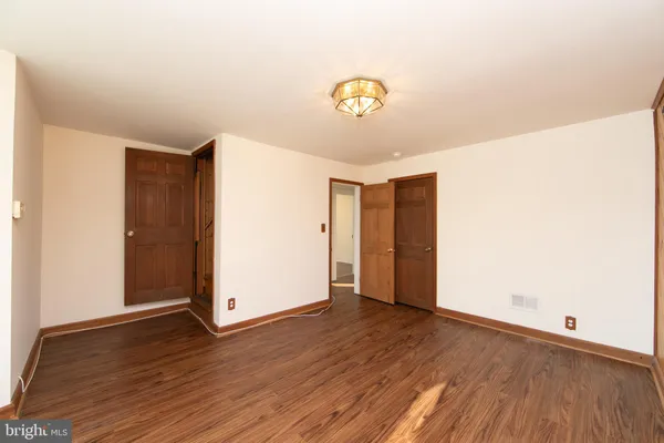 an empty room with wooden floor and hallway
