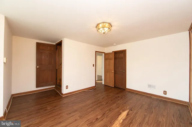 an empty room with wooden floor and hallway