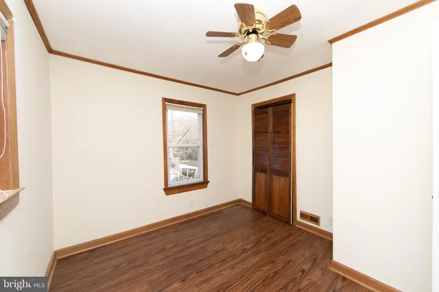 a view of empty room with wooden floor and fan