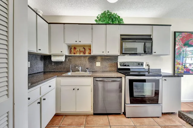 a kitchen with stainless steel appliances granite countertop a sink and a stove