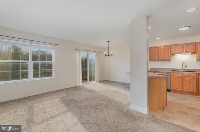 a view of an empty room with kitchen and a window