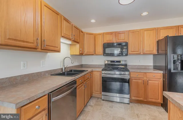 a kitchen with stainless steel appliances granite countertop a stove a refrigerator and a sink