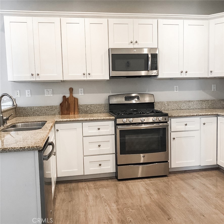 18 Avalon, Unit 5 Irvine, CA 92602 - Photo 3 of 6 a kitchen with granite countertop white cabinets and stainless steel appliances