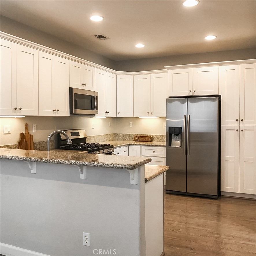 18 Avalon, Unit 5 Irvine, CA 92602 - Photo 4 of 6 a kitchen with stainless steel appliances granite countertop a refrigerator a sink a stove a microwave and white cabinets