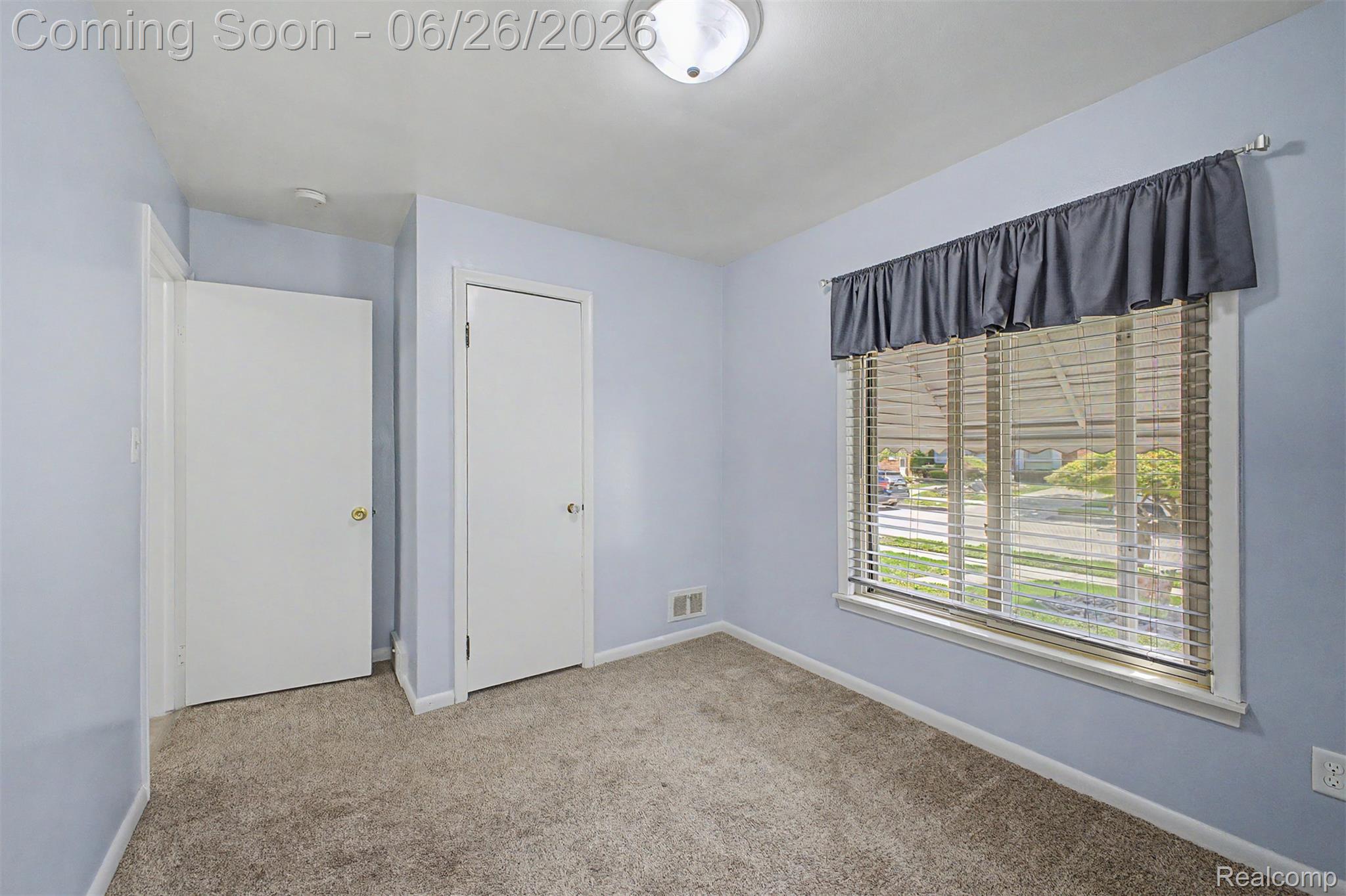 2216 Banner Street Dearborn, MI 48124 - Photo 9 of 34 Carpeted interior room featuring light blue walls, two white panel doors, a window with horizontal blinds, and a semi-flush mount ceiling light