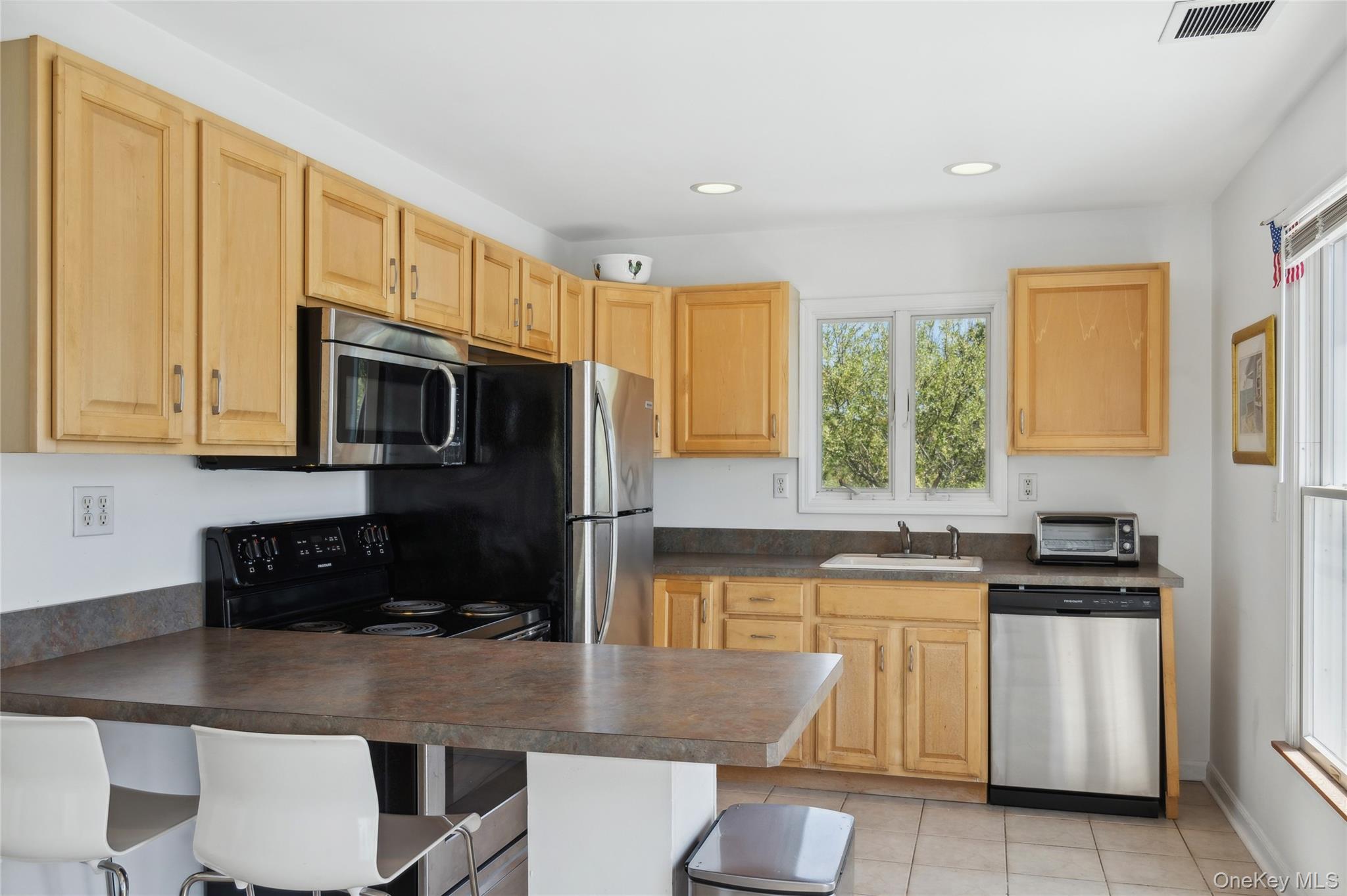 846 Dune Road Westhampton Beach, NY 11978 - Photo 12 of 34 Kitchen featuring a sink, dark countertops, visible vents, light brown cabinets, and appliances with stainless steel finishes
