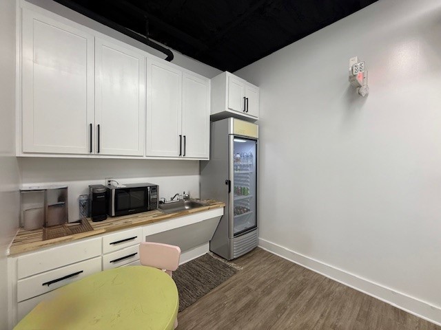 617 Main Street Lexington, TX 78947 - Photo 12 of 25 Kitchen featuring light countertops, black microwave, white cabinetry, Vinyl plank floors and stainless steel refrigerator