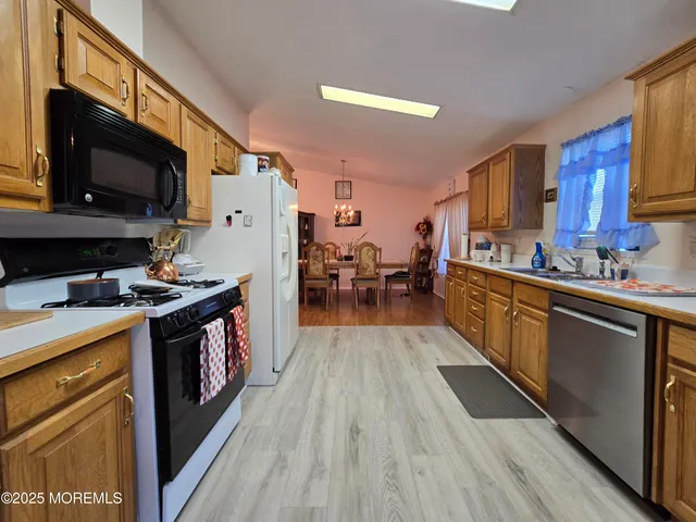 a kitchen with stainless steel appliances a stove top oven a sink dishwasher and a refrigerator with wooden floor