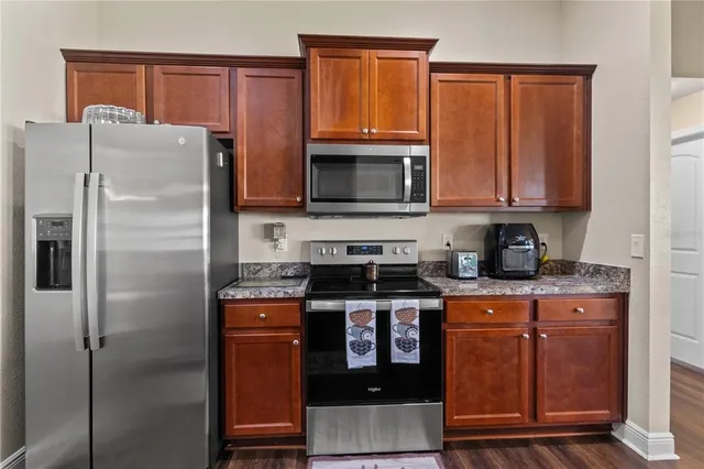 a kitchen with granite countertop a refrigerator stove and microwave