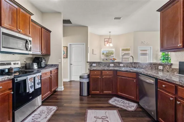 a large kitchen with stainless steel appliances granite countertop a stove a sink dishwasher and a refrigerator