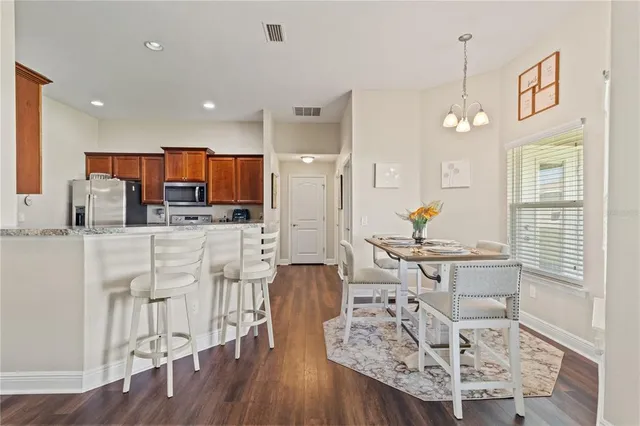 a kitchen with stainless steel appliances kitchen island granite countertop a stove a sink a refrigerator and white cabinets with wooden floor