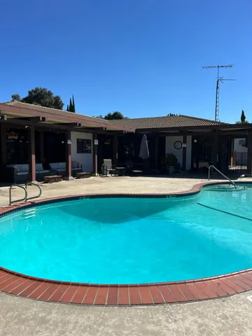 a view of a swimming pool with a lawn chairs under an umbrella