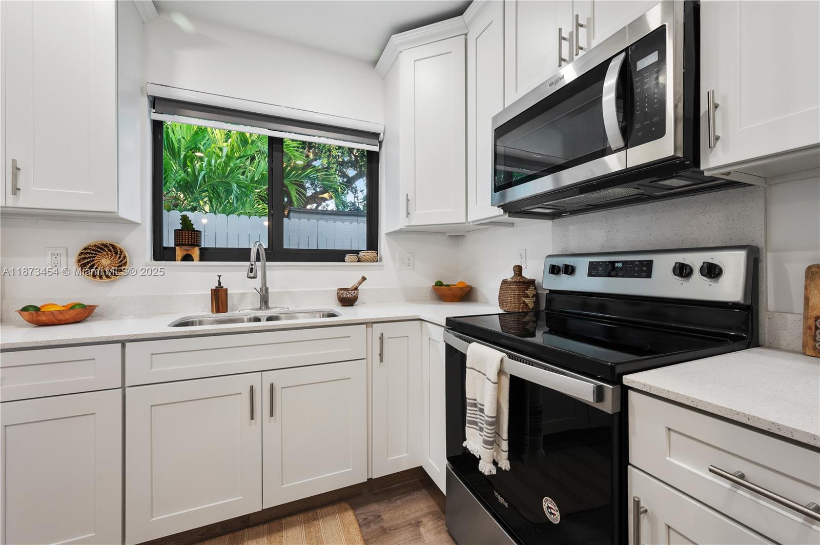 2917 Center Street Miami, FL 33133 - Photo 13 of 32 a kitchen with stainless steel appliances white cabinets granite counter tops and a window