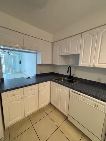 a kitchen with granite countertop white cabinets sink and dishwasher