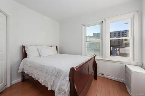 a bedroom with a bed and a window with wooden floor