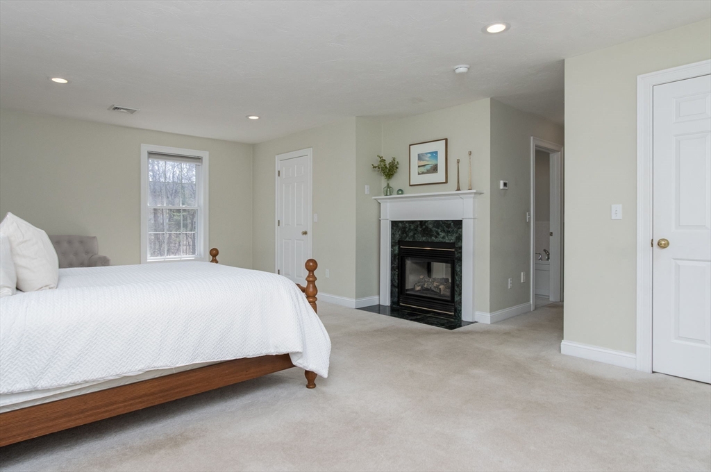 256 Lowell Road Groton, MA 01450 - Photo 23 of 40 a spacious bedroom with a bed and a fireplace