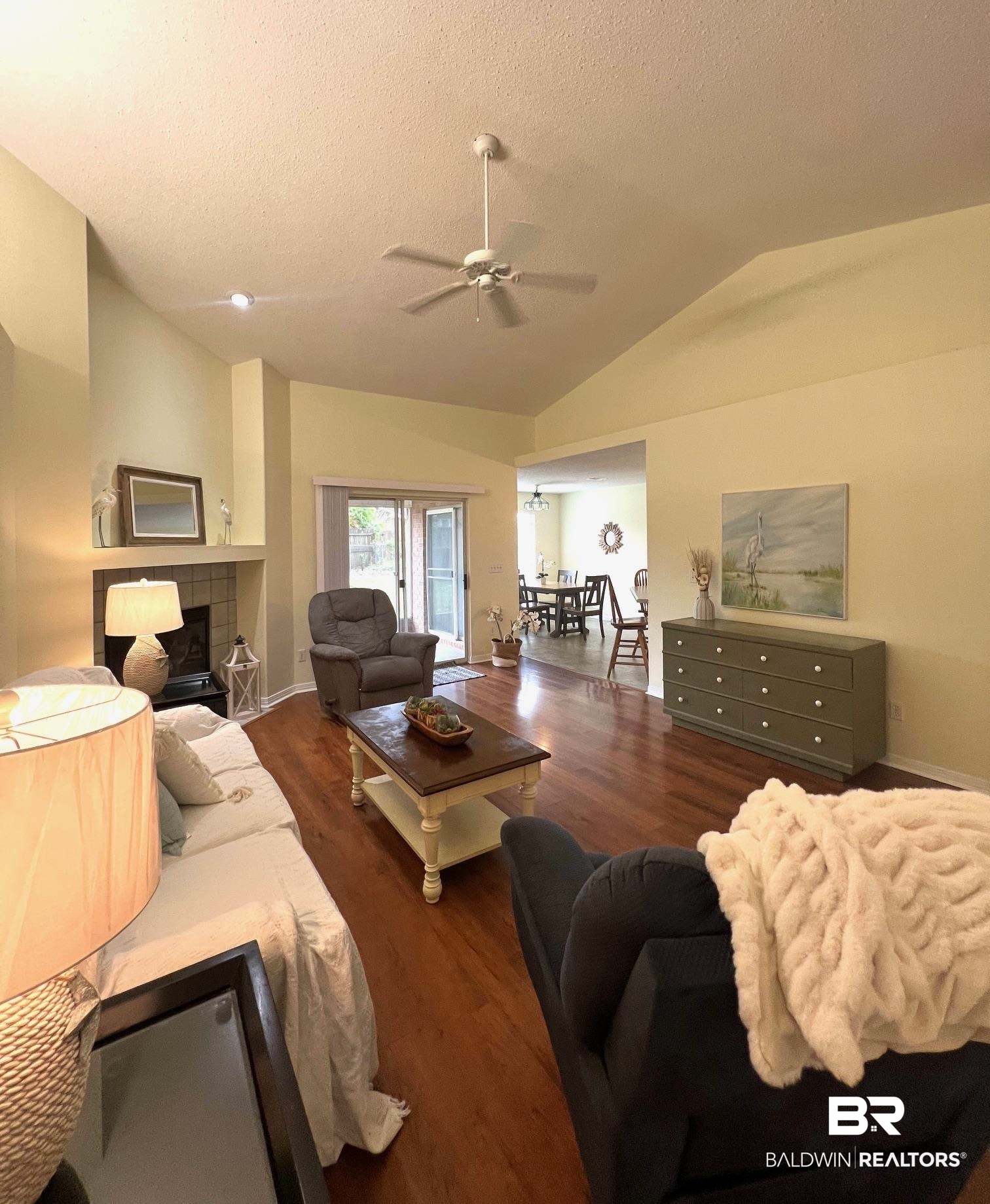 2204 Club House Drive Lillian, AL 36549 - Photo 5 of 38 Living area featuring vaulted ceiling, ceiling fan, wood finished floors, a textured ceiling, and a tiled fireplace