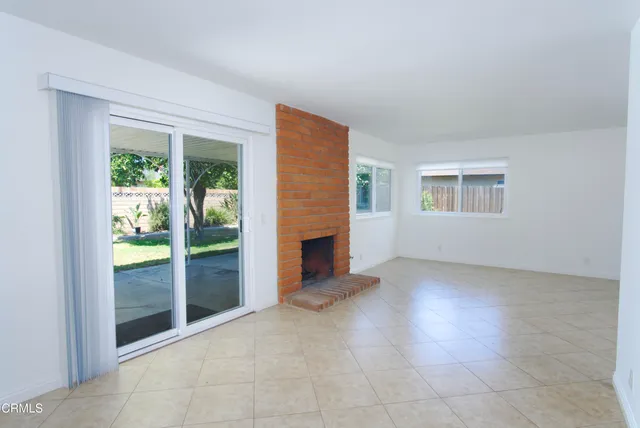 an empty room with windows and fireplace