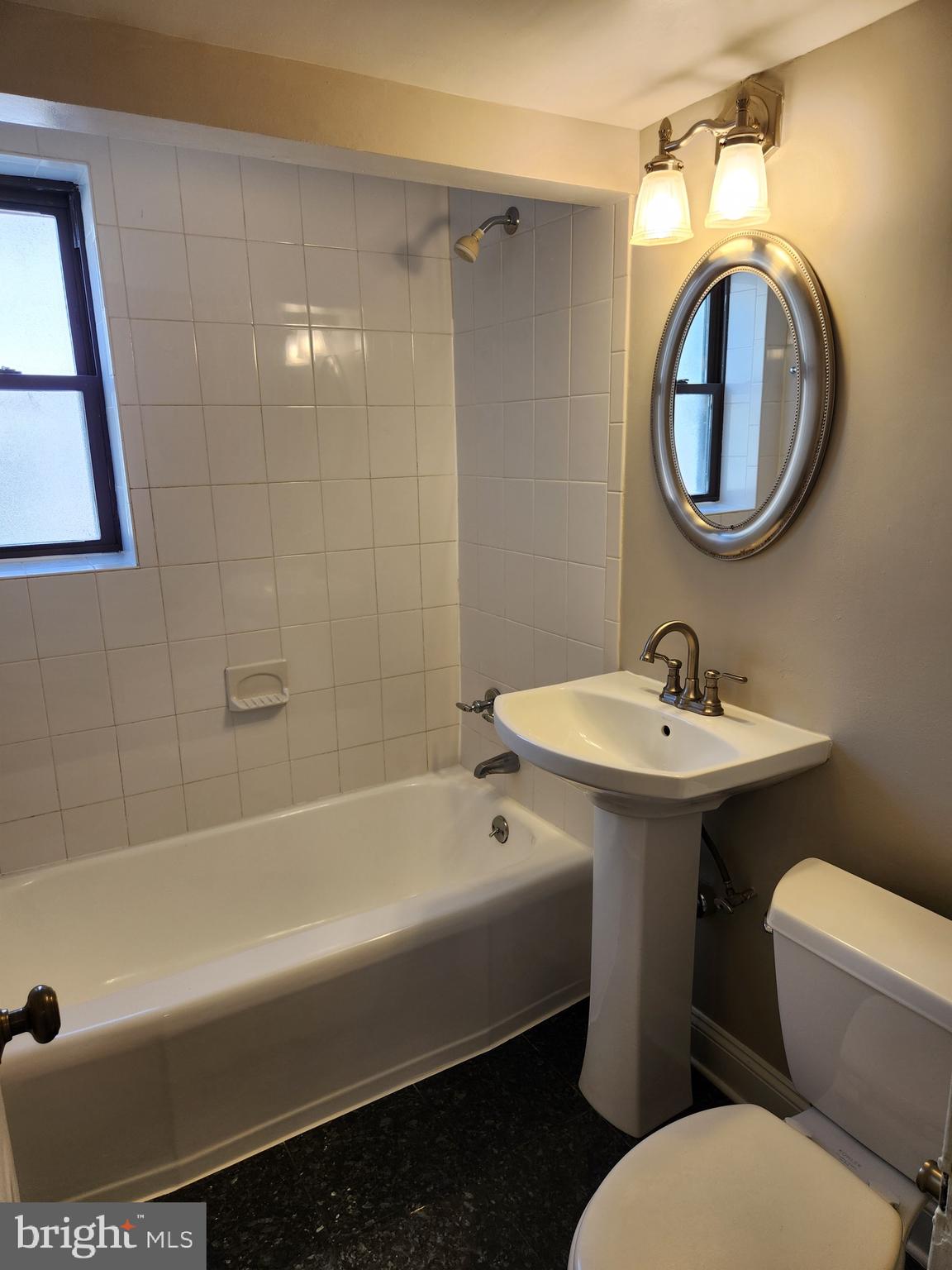 2610 Tunlaw Road Northwest, Unit 103 Washington, DC 20007 - Photo 28 of 36 a bathroom with a sink a mirror bathtub and toilet