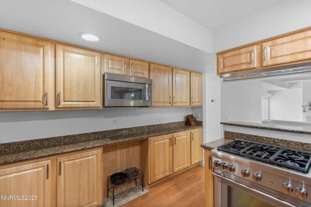 a large kitchen with kitchen island a sink stainless steel appliances wooden floor and a counter top space
