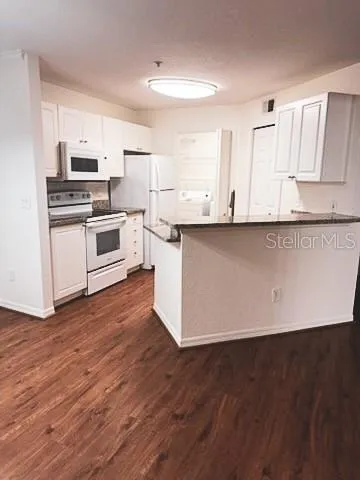 a kitchen with granite countertop white cabinets and wooden floor