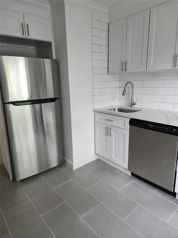 a kitchen with a sink a refrigerator and cabinets