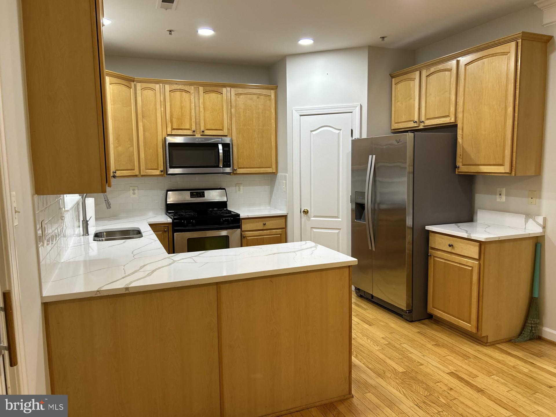 14030 Castle Ridge Way, Unit 27 Silver Spring, MD 20904 - Photo 5 of 19 a kitchen with wooden cabinets and refrigerator