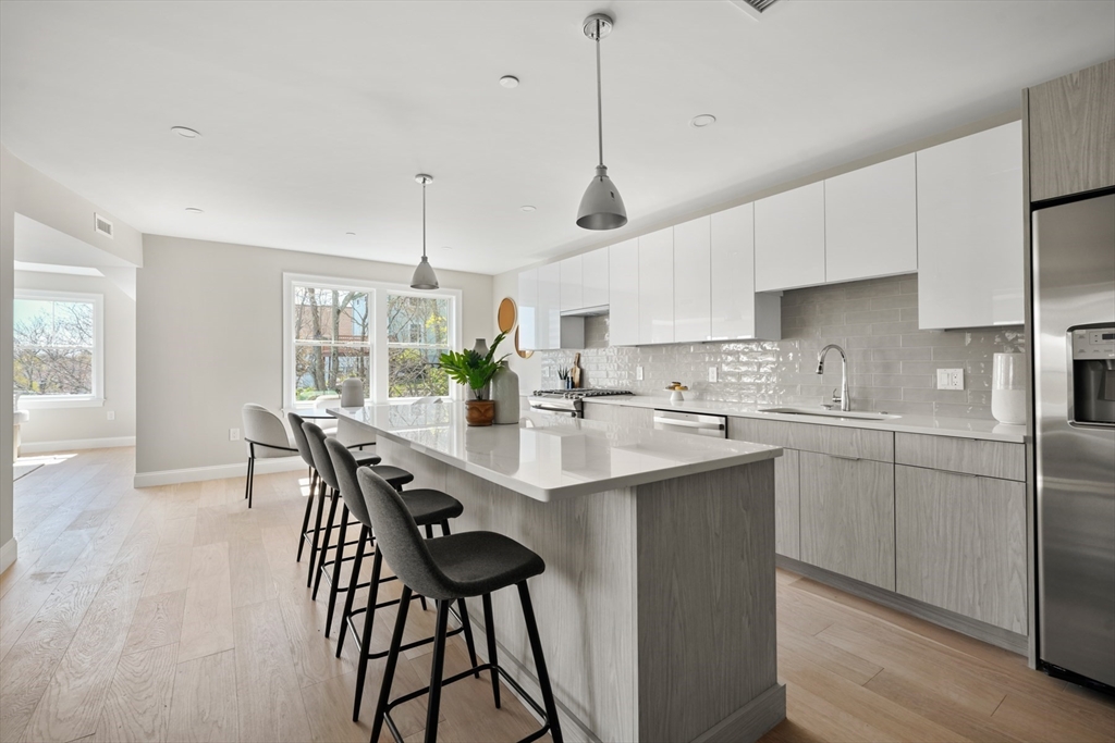 a kitchen with stainless steel appliances granite countertop a dining table chairs sink and white cabinets