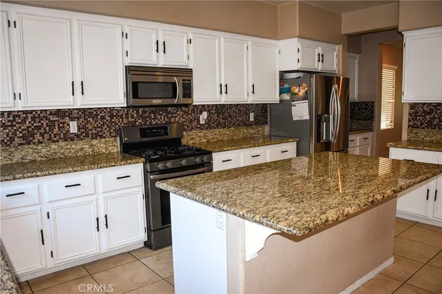 a kitchen with stainless steel appliances granite countertop a refrigerator and a stove top oven