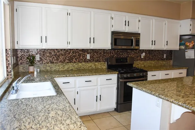 a kitchen with granite countertop white cabinets and stainless steel appliances