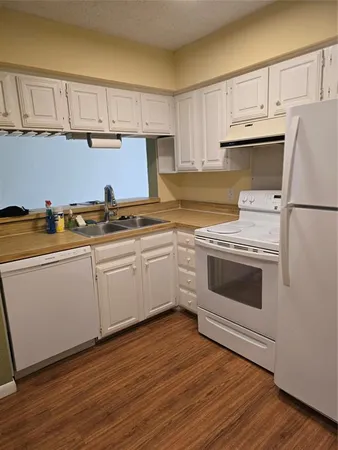 a kitchen with cabinets stainless steel appliances and wooden floor