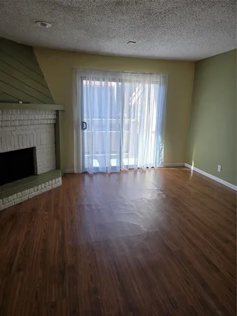 an empty room with wooden floor fireplace and windows